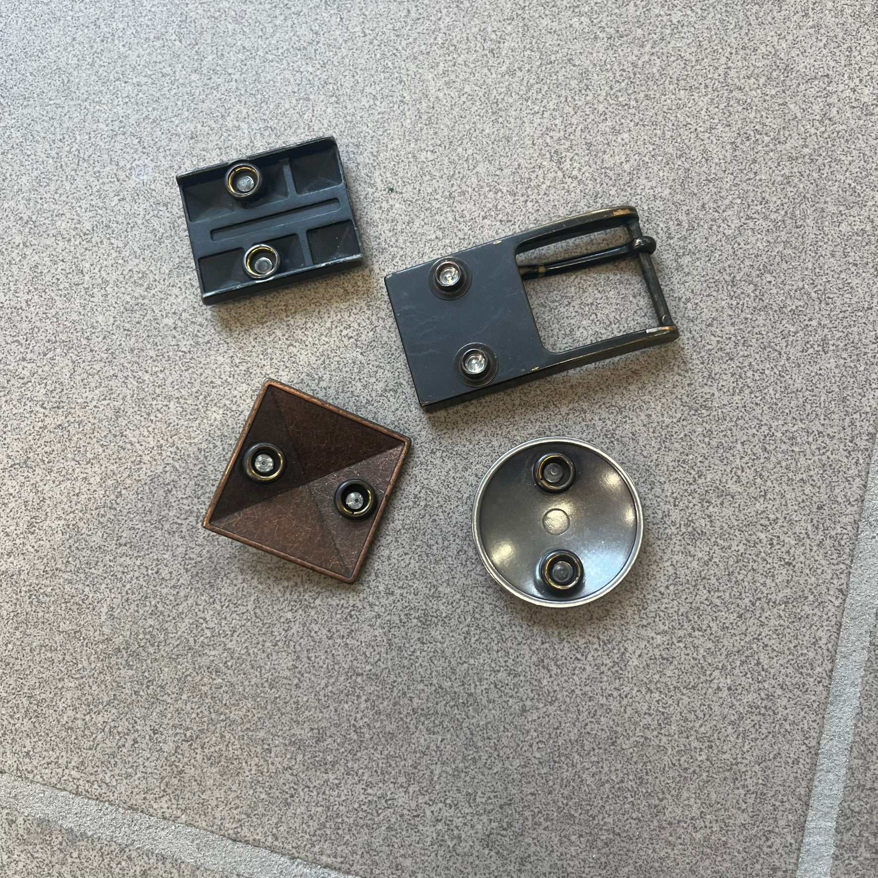 Diesel 2000s Changeable Buckles Set includes a Diesel belt buckle system with interchangeable front pieces. The base buckle features two snap buttons that allow different designs to be attached. The set includes three interchangeable buckles: a Diesel logo design with studs, a circular buckle with the Mohawk character logo, and a bronze pyramid logo design. Comes with the original dust bag.

