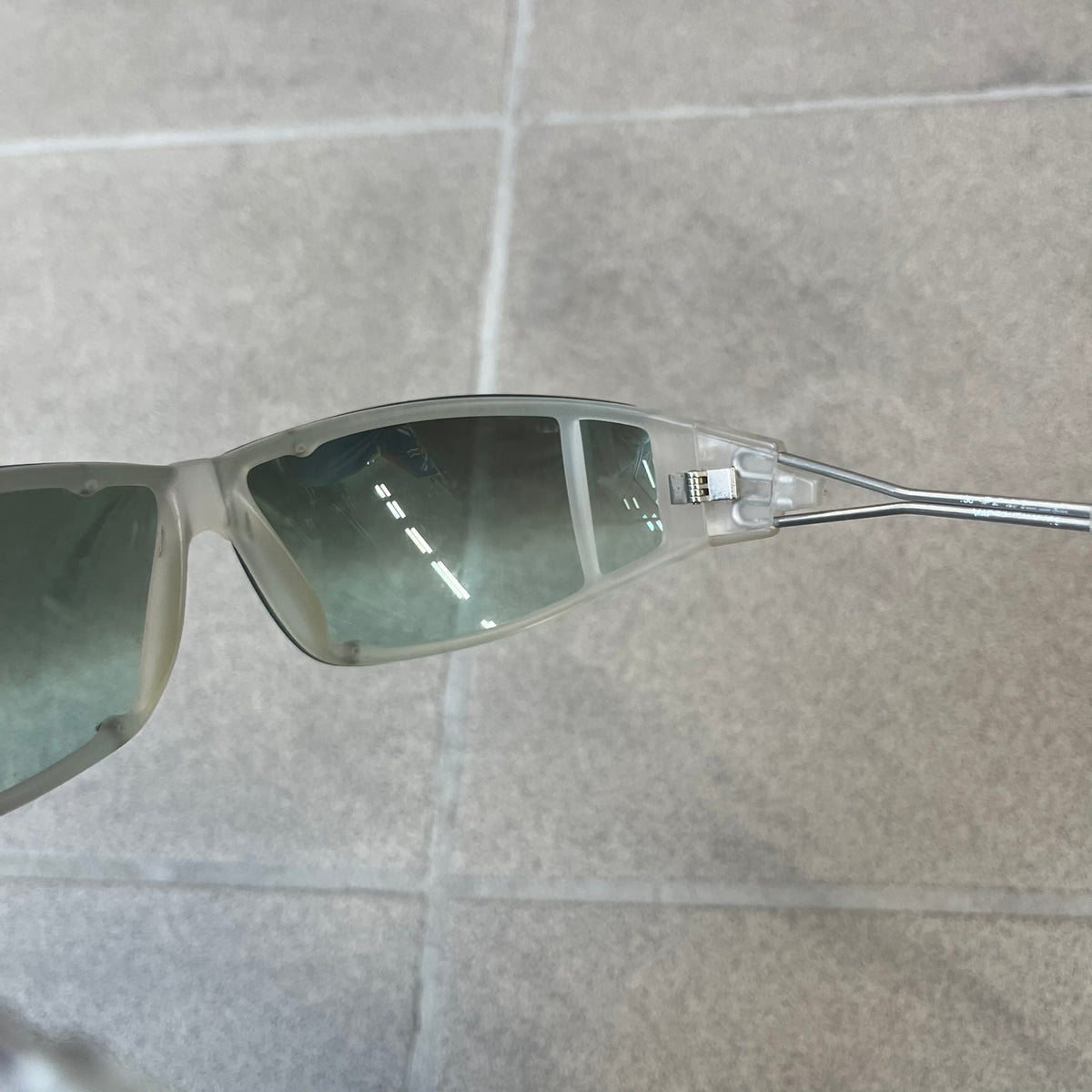 Diesel 2000's Clear Jumbo Sunglasses feature thin silver-tone wire temples with clear plastic sections extending over the ends and front of the frame. The lenses have a grey-tinted transparent finish, with visible screws on the front. A small silver Diesel logo is placed on the side, with white Diesel text printed in the corner of one lens.

