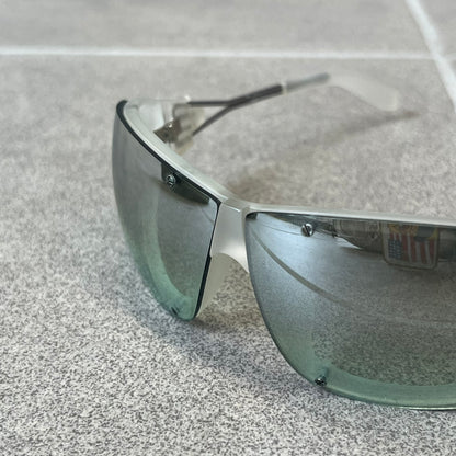 Diesel 2000's Clear Jumbo Sunglasses feature thin silver-tone wire temples with clear plastic sections extending over the ends and front of the frame. The lenses have a grey-tinted transparent finish, with visible screws on the front. A small silver Diesel logo is placed on the side, with white Diesel text printed in the corner of one lens.
