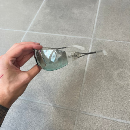 Diesel 2000's Clear Jumbo Sunglasses feature thin silver-tone wire temples with clear plastic sections extending over the ends and front of the frame. The lenses have a grey-tinted transparent finish, with visible screws on the front. A small silver Diesel logo is placed on the side, with white Diesel text printed in the corner of one lens.
