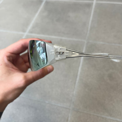 Diesel 2000's Clear Jumbo Sunglasses feature thin silver-tone wire temples with clear plastic sections extending over the ends and front of the frame. The lenses have a grey-tinted transparent finish, with visible screws on the front. A small silver Diesel logo is placed on the side, with white Diesel text printed in the corner of one lens.
