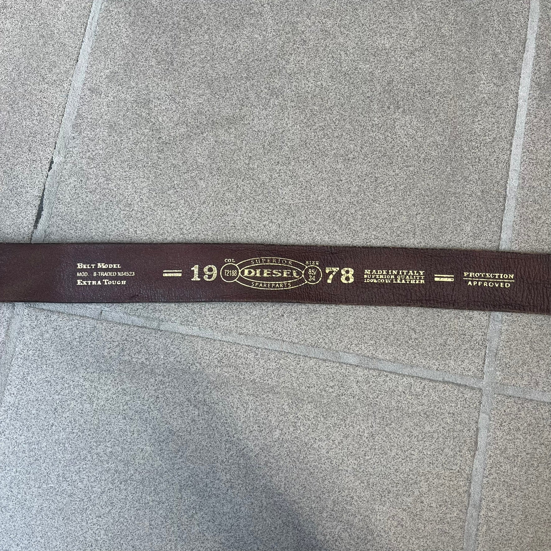 Diesel 2000's Only The Brave Brown Leather Belt features a brown 100% cow leather construction with a bronze-tone buckle. The buckle has engraved Diesel branding, including “Only The Brave Since 1978” text and other details. The belt is marked “Extra Tough,” with gold Diesel text printed on the inside. Made in Italy.
