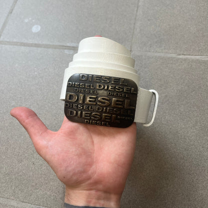 Diesel 2000s Repeat Logo White Leather Belt features a white leather strap with a rectangular bronze-tone buckle. The buckle is decorated with a repeating Diesel text logo pattern in different sizes, creating a layered branded design. Made in Italy.
