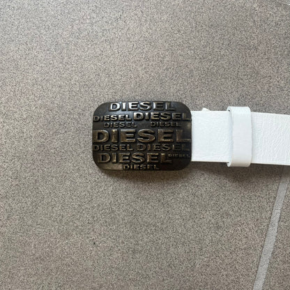 Diesel 2000s Repeat Logo White Leather Belt features a white leather strap with a rectangular bronze-tone buckle. The buckle is decorated with a repeating Diesel text logo pattern in different sizes, creating a layered branded design. Made in Italy.
