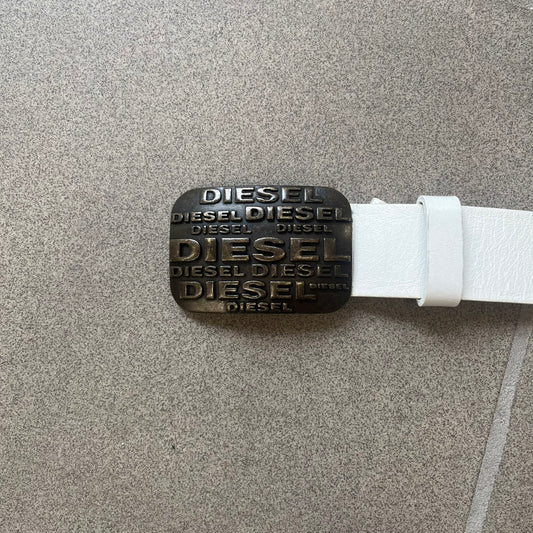 Diesel 2000s Repeat Logo White Leather Belt features a white leather strap with a rectangular bronze-tone buckle. The buckle is decorated with a repeating Diesel text logo pattern in different sizes, creating a layered branded design. Made in Italy.
