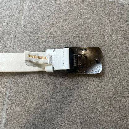 Diesel 2000s Repeat Logo White Leather Belt features a white leather strap with a rectangular bronze-tone buckle. The buckle is decorated with a repeating Diesel text logo pattern in different sizes, creating a layered branded design. Made in Italy.
