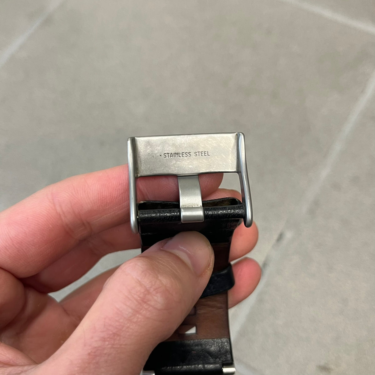 Diesel 2000’s Square DZ2107 Analog Watch has a square stainless steel case with an engraved Diesel logo in the bottom right corner. The circular black dial has orange hands, and the watch is fitted with a black leather strap.