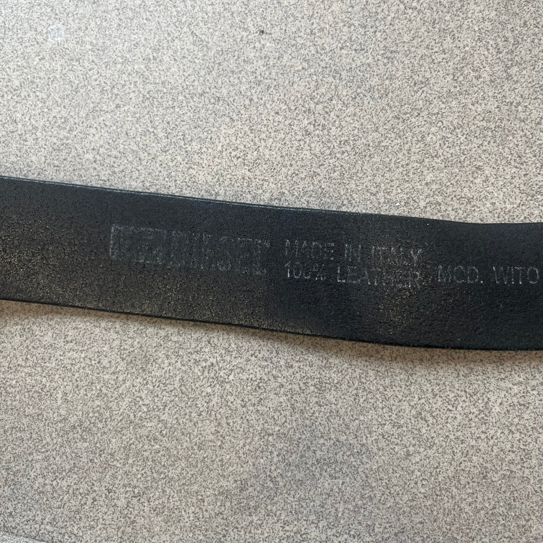 Diesel 2000s Vintage Buckle Leather Belt features a black leather strap made in Italy. The belt has a large rectangular metal buckle designed to look like a worn metal sheet, with a Diesel logo formed from small perforated holes. The buckle includes visible screws on the sides and the belt is made from 100% leather.
