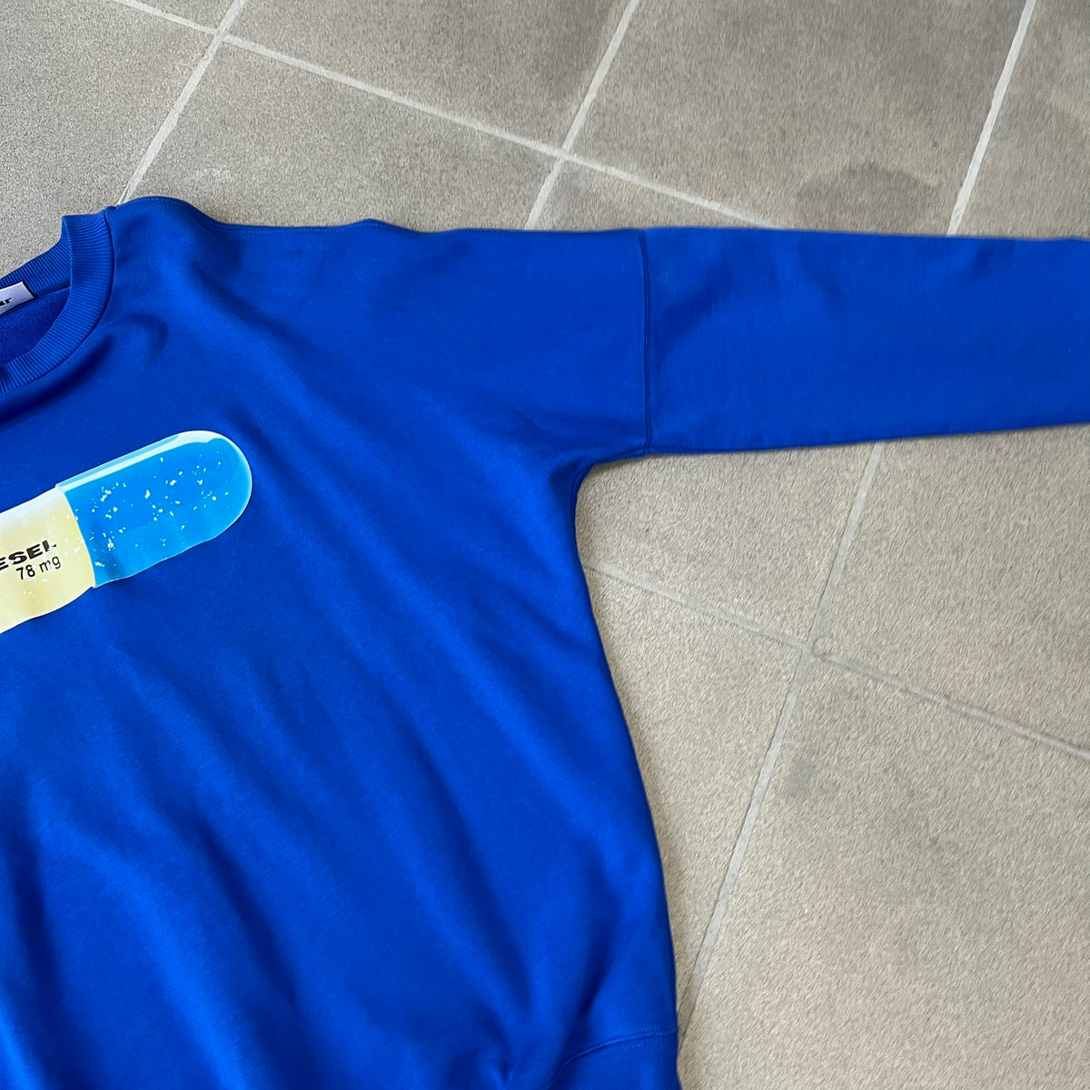 Diesel 2017 "78 mg Pill" Blue Crewneck is a blue, 100% cotton crewneck featuring a large pill graphic in yellow and blue, with black "DIESEL 78 mg" text printed on the yellow half.