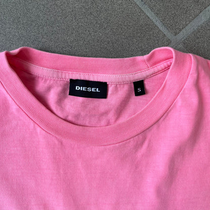 Diesel DLVERANCE Bright Pink Tee features a 100% cotton jersey construction with a fluorescent pink pigment-dyed finish. The front has a rubberised “DLVERANCE” graphic, with a small rubber “Copyright” logo on the lower back.