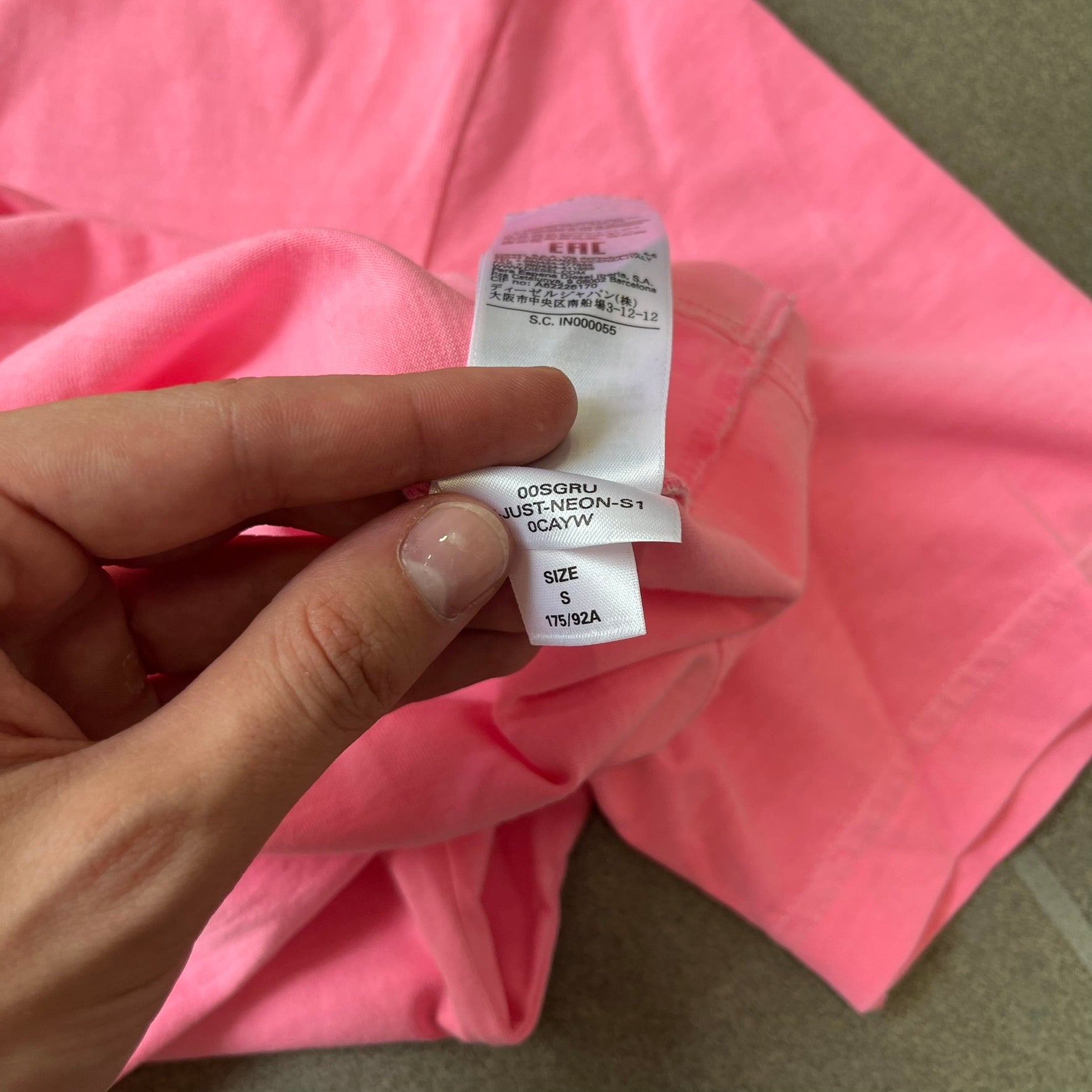 Diesel DLVERANCE Bright Pink Tee features a 100% cotton jersey construction with a fluorescent pink pigment-dyed finish. The front has a rubberised “DLVERANCE” graphic, with a small rubber “Copyright” logo on the lower back.