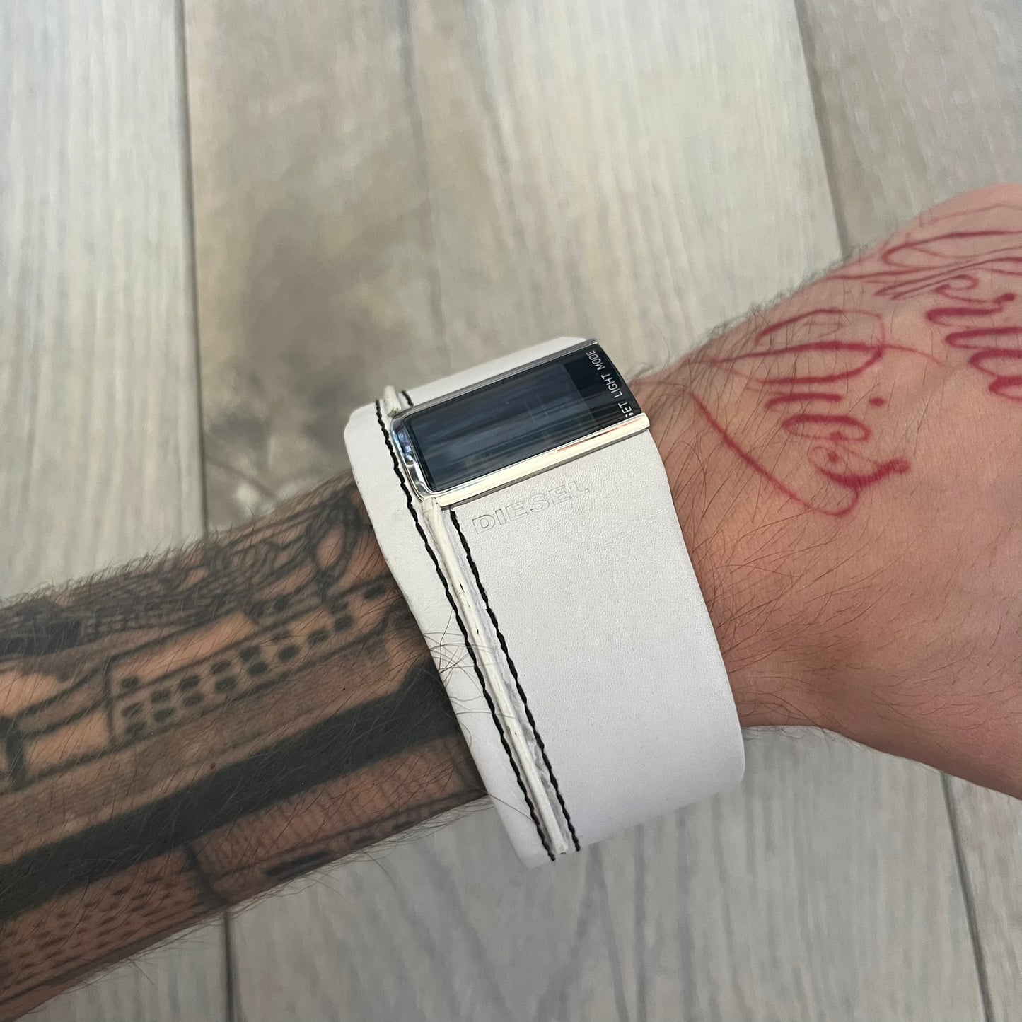 Diesel DZ7054 White Leather Strap Digital Watch features a White leather strap and a black digital display housed in a silver rectangular case. The watch includes a backlight, Arabic numeral indices, and a deployant closure, with a stainless steel case back engraved with Diesel branding and model number DZ-7090. It is water resistant up to 50 meters (5 ATM) and combines industrial design with functional quartz digital movement.&nbsp;