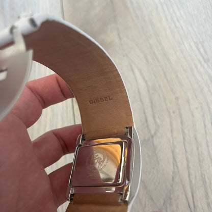 Diesel DZ7054 White Leather Strap Digital Watch features a White leather strap and a black digital display housed in a silver rectangular case. The watch includes a backlight, Arabic numeral indices, and a deployant closure, with a stainless steel case back engraved with Diesel branding and model number DZ-7090. It is water resistant up to 50 meters (5 ATM) and combines industrial design with functional quartz digital movement.&nbsp;