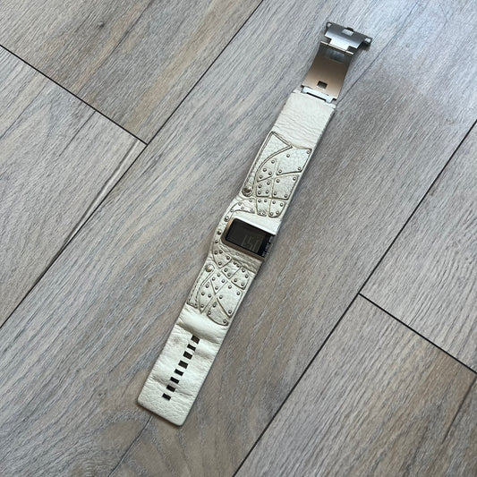 Diesel DZ7068 Studded Leather Strap Digital Watch features a white leather patchwork strap accented with small metal studs and a black digital display housed in a silver rectangular case. The watch includes a backlight, Arabic numeral indices, and a deployant closure, with a stainless steel case back engraved with Diesel branding and model number DZ-7068. It is water resistant up to 50 meters (5 ATM) and combines industrial design with functional quartz digital movement.