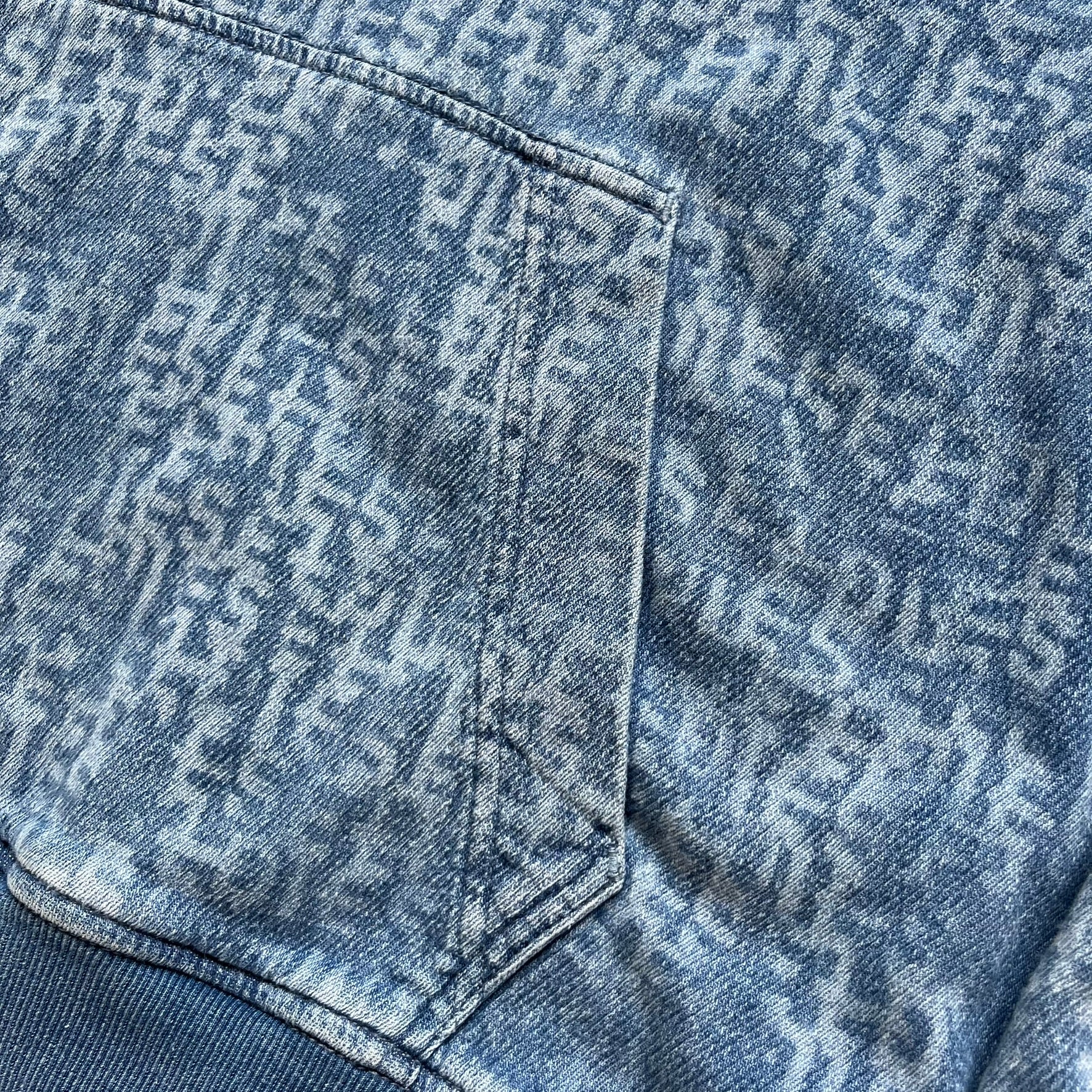 Diesel “Denim” Logo Blue Hoodie is a blue hooded sweatshirt designed with a denim-inspired colorway and washed effect throughout. The fabric features varying light and dark blue shades to mimic the appearance of worn denim, along with an all-over Diesel text pattern in a slightly lighter tone. A small red Diesel patch is placed on the chest, while the cuffs and hem are finished in a contrasting navy color.&nbsp;