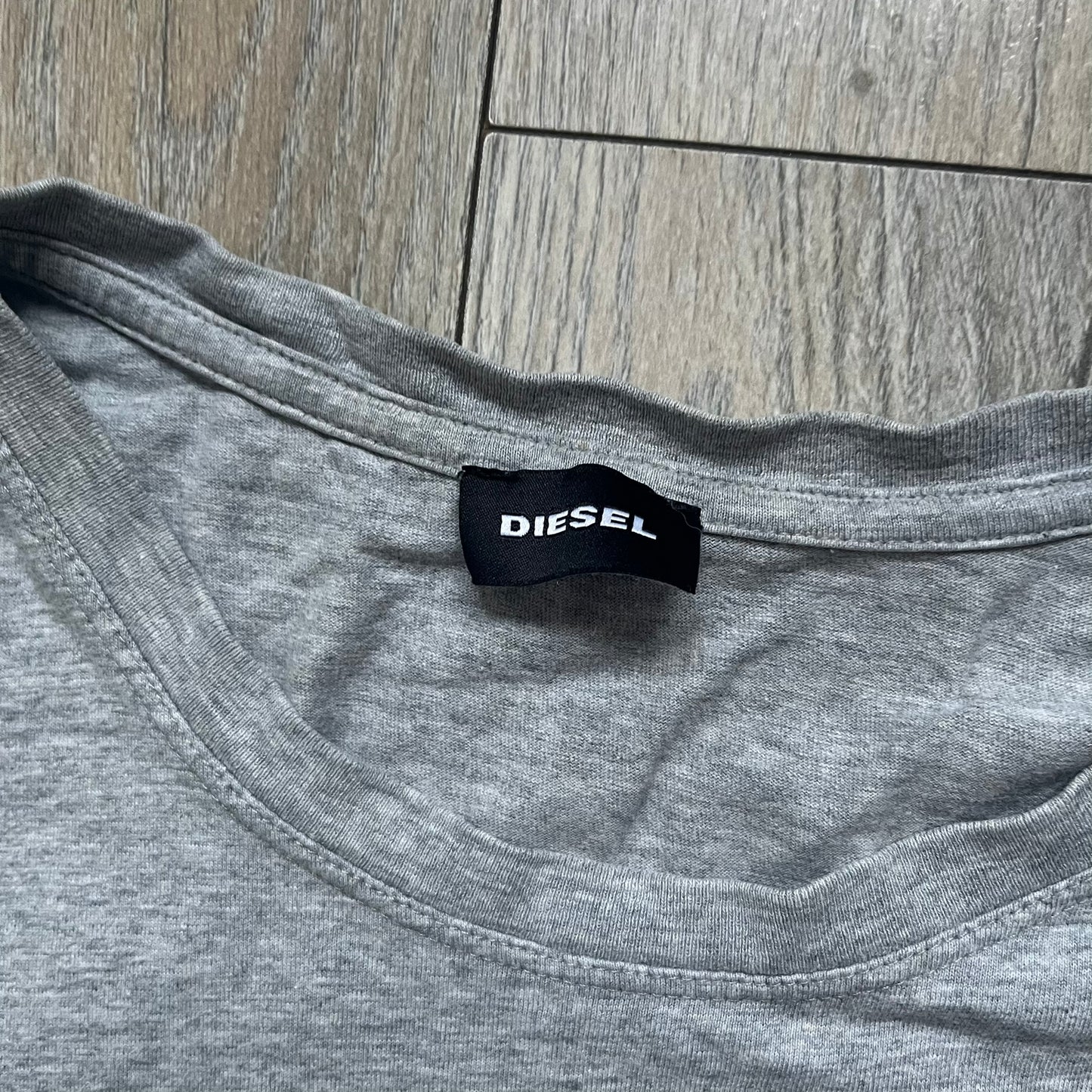 Diesel Music 1978 Gray Tee is a gray T-shirt featuring a large hand-drawn style “Diesel Music 1978” print on the front with additional text below. Made from 100% cotton, it has a crew neckline and short sleeves. The print is white, contrasting with the gray fabric.