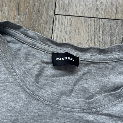 Diesel Music 1978 Gray Tee is a gray T-shirt featuring a large hand-drawn style “Diesel Music 1978” print on the front with additional text below. Made from 100% cotton, it has a crew neckline and short sleeves. The print is white, contrasting with the gray fabric.