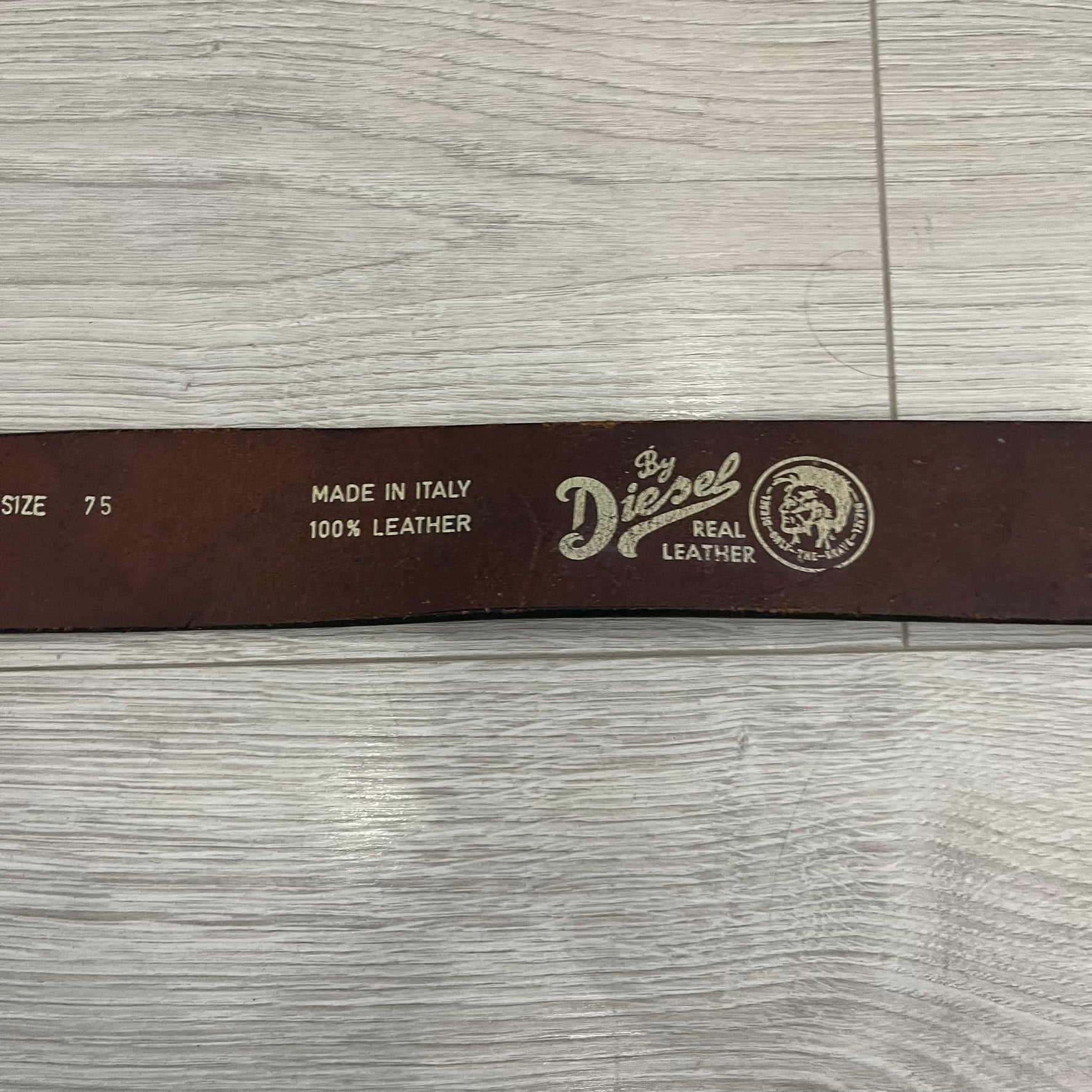 Diesel “Only The Brave” leather belt crafted in Italy from 100% brown leather and finished with a metal buckle with leather front. The buckle displays the Mohawk Warrior helmet motif with surrounding Diesel branding for an iconic look.