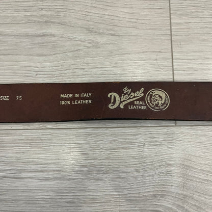 Diesel “Only The Brave” leather belt crafted in Italy from 100% brown leather and finished with a metal buckle with leather front. The buckle displays the Mohawk Warrior helmet motif with surrounding Diesel branding for an iconic look.