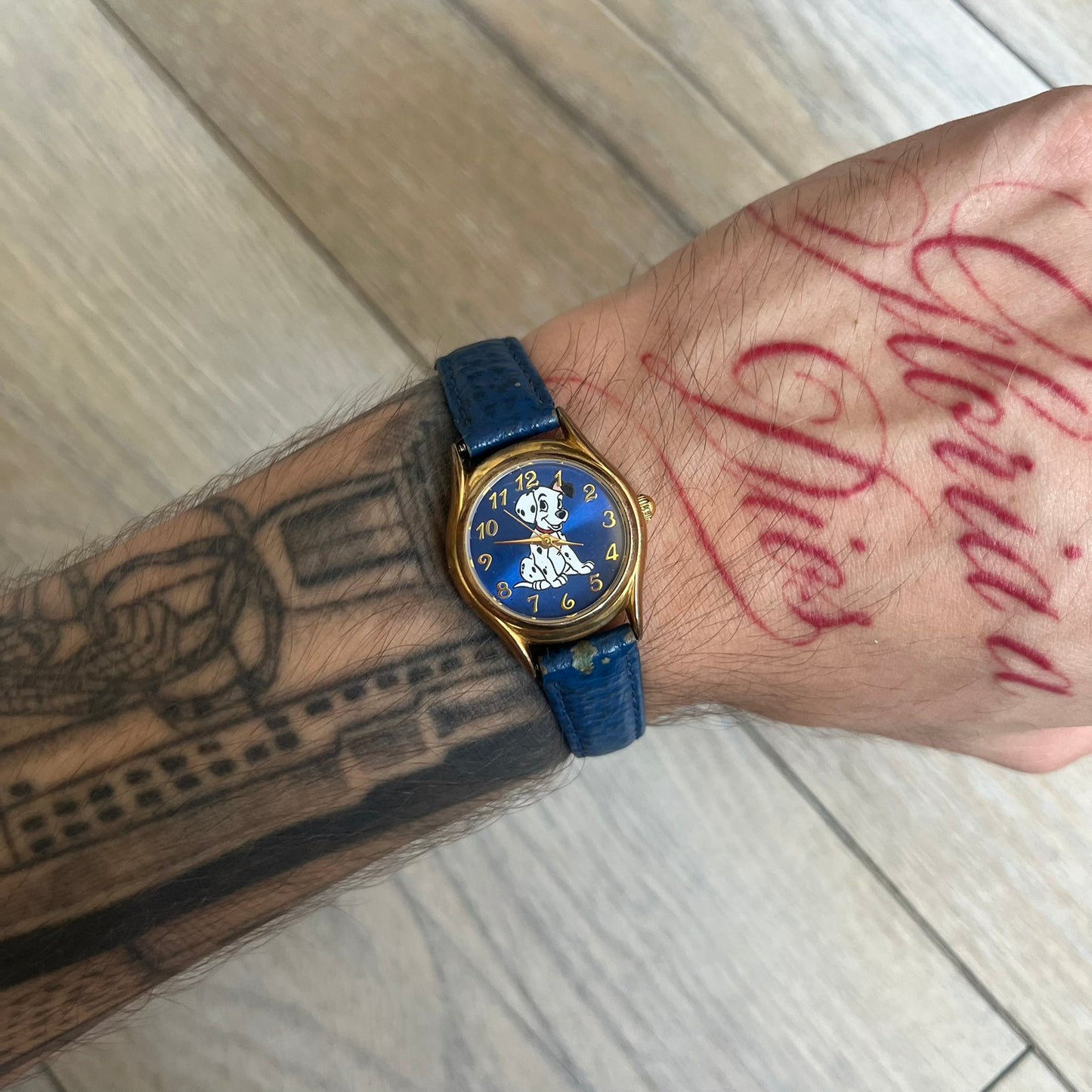 Disney 101 Dalmatians 1990s Blue Analog Watch features a navy leather strap, gold-tone case, and navy dial. The dial includes gold hour markers and hands with a Dalmatian character graphic in the center. The case back is marked as made exclusively for the Disney Store and includes a Japan movement marking. The watch is sized for smaller wrists.
