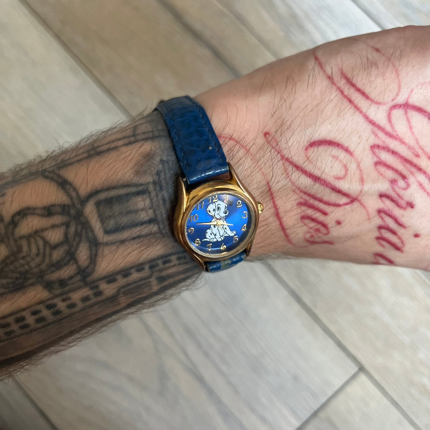 Disney 101 Dalmatians 1990s Blue Analog Watch features a navy leather strap, gold-tone case, and navy dial. The dial includes gold hour markers and hands with a Dalmatian character graphic in the center. The case back is marked as made exclusively for the Disney Store and includes a Japan movement marking. The watch is sized for smaller wrists.
