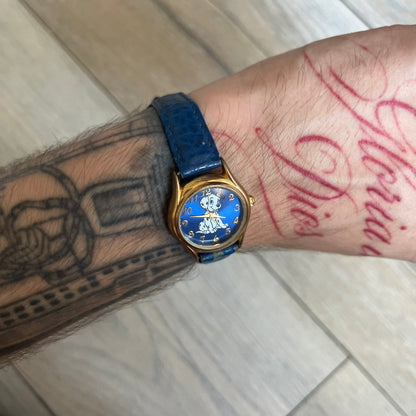 Disney 101 Dalmatians 1990s Blue Analog Watch features a navy leather strap, gold-tone case, and navy dial. The dial includes gold hour markers and hands with a Dalmatian character graphic in the center. The case back is marked as made exclusively for the Disney Store and includes a Japan movement marking. The watch is sized for smaller wrists.

