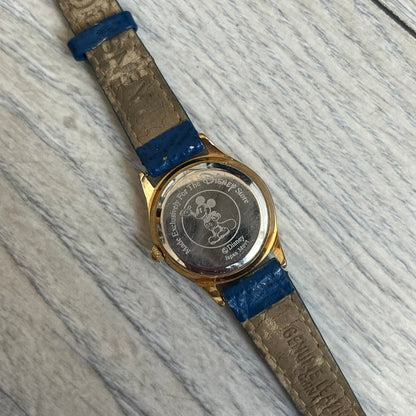Disney 101 Dalmatians 1990s Blue Analog Watch features a navy leather strap, gold-tone case, and navy dial. The dial includes gold hour markers and hands with a Dalmatian character graphic in the center. The case back is marked as made exclusively for the Disney Store and includes a Japan movement marking. The watch is sized for smaller wrists.
