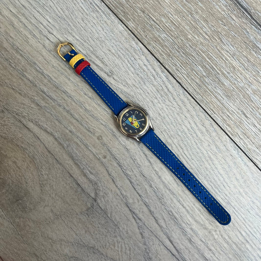 Disney Winnie-the-Pooh 1990s Analog Watch features blue leather straps, a gold-tone case, and a navy dial. The dial displays gold hour markers with Winnie the Pooh illustrated in the center. The case back is marked with official Disney licensing and indicates it was made exclusively for Disney. This watch is sized for smaller wrists.
