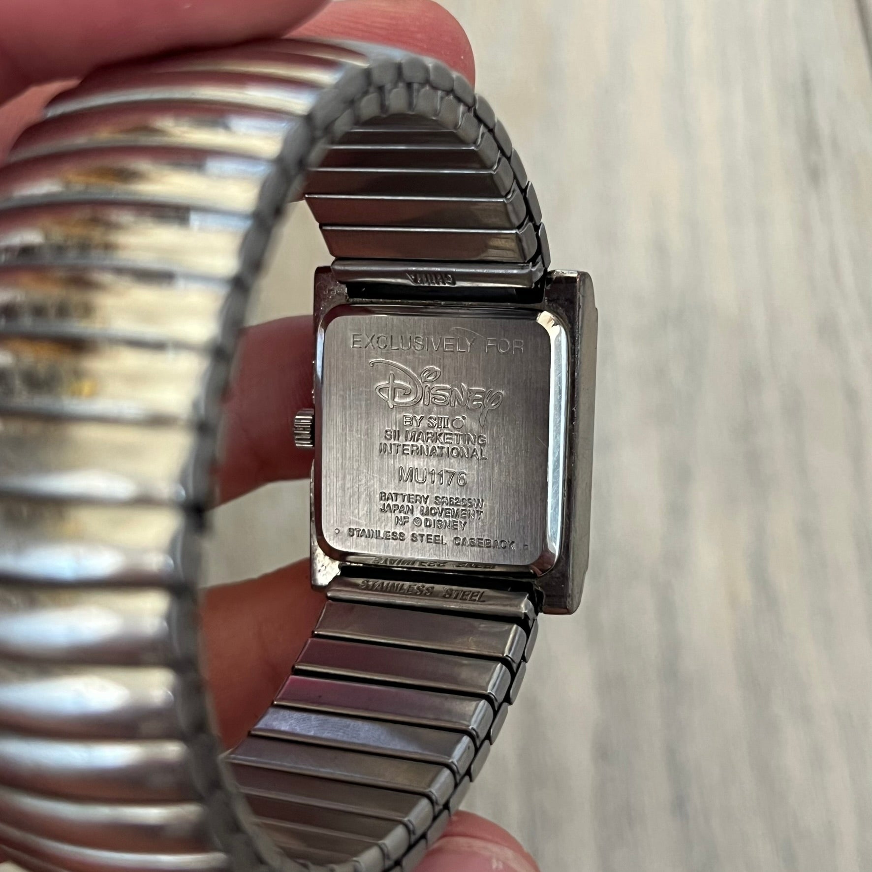 Disney Winnie-the-Pooh Eeyore 1990's Analog Watch is a stainless steel watch with a shiny finish and a stretch expansion bracelet made from connected metal links. The dial features silver numerals with a graphic of Eeyore. The caseback includes "Exclusively for Disney". Bracelet is for smaller wrists.