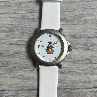 Disneyland Paris 1997 “5 Years Anniversary” Analog Watch features a silver-tone metal case, white dial, and white leather straps. The dial displays a colorful Disney castle graphic with “5 Years” text commemorating the anniversary of the Paris location. The case back is marked “Disneyland Paris Avronel” and indicates production by Avronel for Disney. The watch is rated for 3 ATM water resistance.