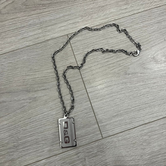 Dolce &amp; Gabbana Propaganda Dog Tag Necklace, featuring a silver stainless steel square tag with four visible screws and the D&amp;G logo engraved on the front. The tag hangs from a durable cable chain, combining sturdy construction with clean, industrial-inspired detailing.
