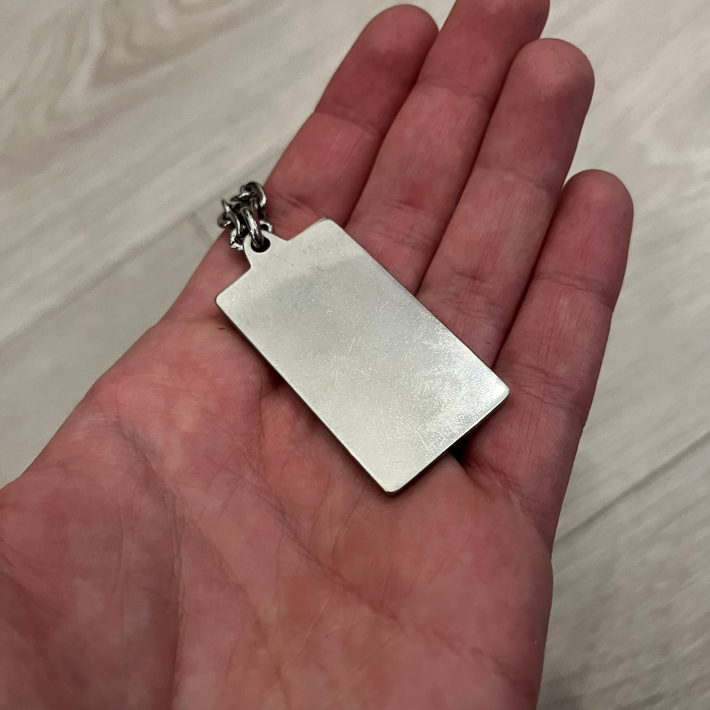 Dolce &amp; Gabbana Propaganda Dog Tag Necklace, featuring a silver stainless steel square tag with four visible screws and the D&amp;G logo engraved on the front. The tag hangs from a durable cable chain, combining sturdy construction with clean, industrial-inspired detailing.