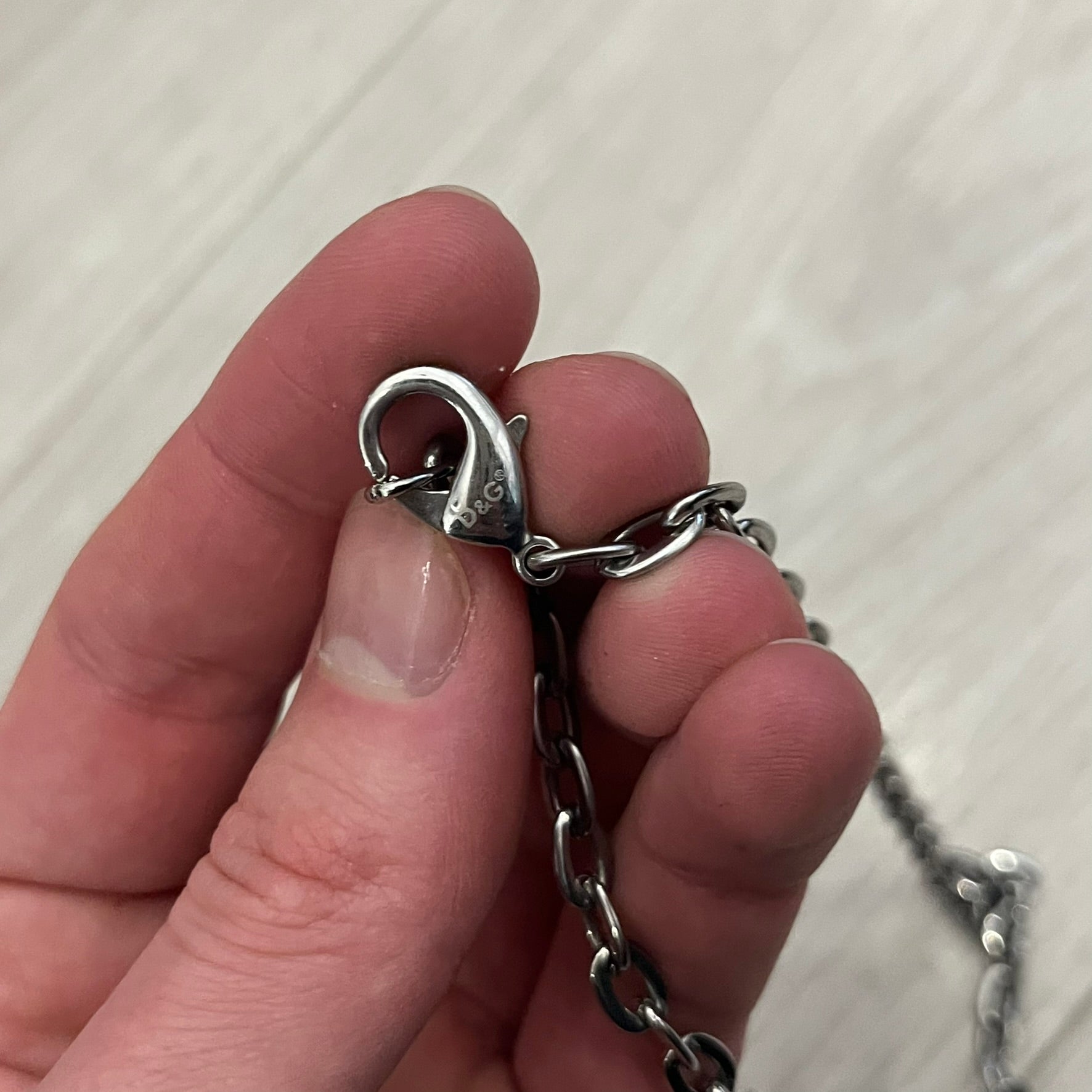 Dolce &amp; Gabbana Propaganda Dog Tag Necklace, featuring a silver stainless steel square tag with four visible screws and the D&amp;G logo engraved on the front. The tag hangs from a durable cable chain, combining sturdy construction with clean, industrial-inspired detailing.