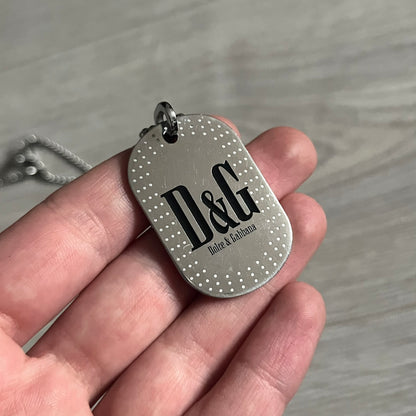 Dolce &amp; Gabbana Cowboy Dog Tag Necklace, model DJ0633. Features a silver-tone metal ball chain and a dog tag with black cowboy-style D&amp;G logo and small “Dolce &amp; Gabbana” text underneath. The front of the tag is patterned with subtle white dots for added detail.