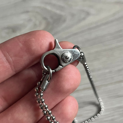 Dolce &amp; Gabbana Cowboy Dog Tag Necklace, model DJ0633. Features a silver-tone metal ball chain and a dog tag with black cowboy-style D&amp;G logo and small “Dolce &amp; Gabbana” text underneath. The front of the tag is patterned with subtle white dots for added detail.
