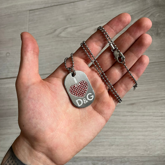 Dolce &amp; Gabbana "I ❤️ D&amp;G" Dog Tag Necklace with a silver stainless steel ball chain, featuring a dog tag engraved with a white "I," a red crystal heart, and "D&amp;G" text below, forming the "I ❤️ D&amp;G" design. A playful and collectible vintage piece.