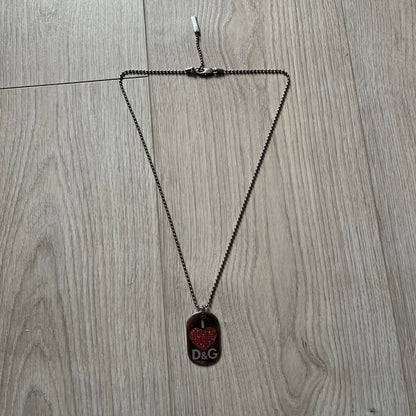 Dolce &amp; Gabbana "I ❤️ D&amp;G" Dog Tag Necklace with a silver stainless steel ball chain, featuring a dog tag engraved with a white "I," a red crystal heart, and "D&amp;G" text below, forming the "I ❤️ D&amp;G" design. A playful and collectible vintage piece.