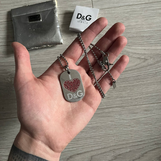 Dolce &amp; Gabbana "I ❤️ D&amp;G" Dog Tag Necklace with a silver stainless steel ball chain, featuring a dog tag engraved with a white "I," a red crystal heart, and "D&amp;G" text below, forming the "I ❤️ D&amp;G" design. A playful and collectible vintage piece. Comes with a dustbag.