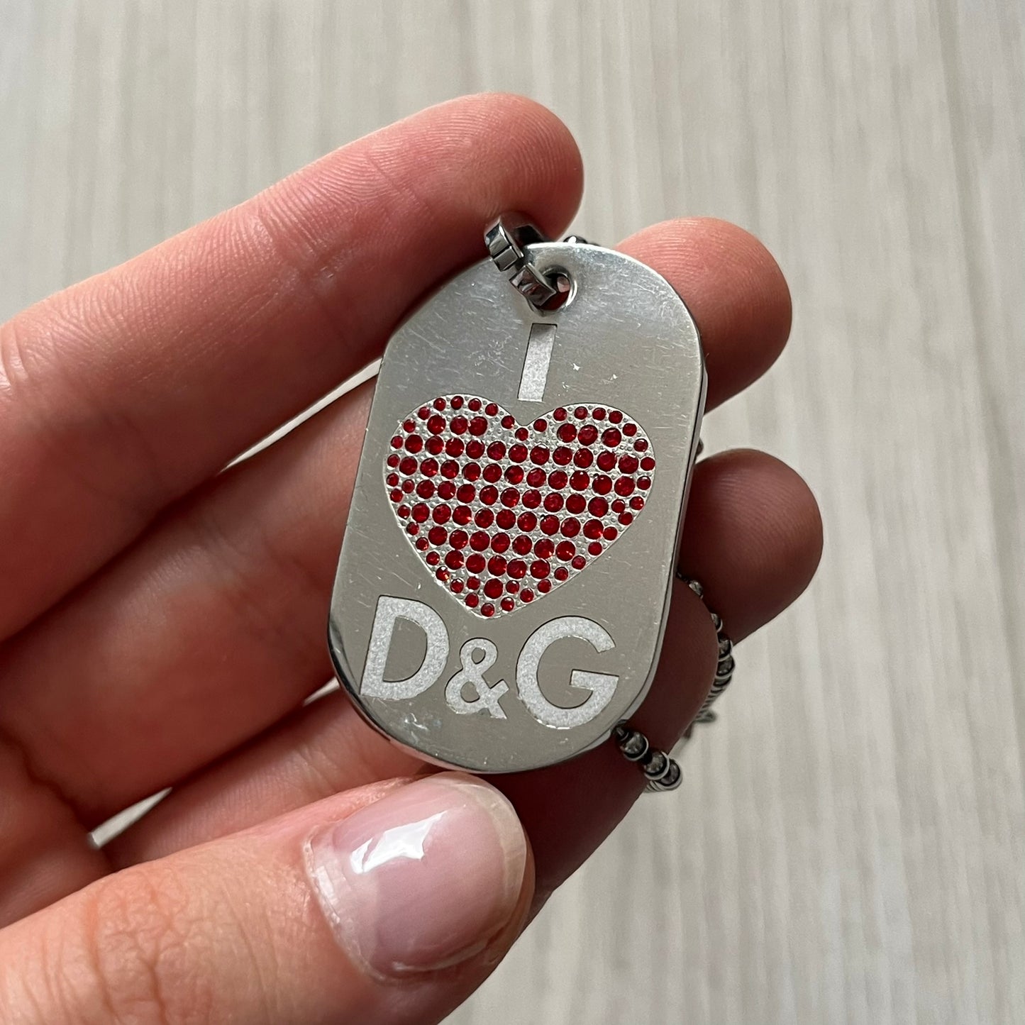 Dolce &amp; Gabbana "I ❤️ D&amp;G" Dog Tag Necklace with a silver stainless steel ball chain, featuring a dog tag engraved with a white "I," a red crystal heart, and "D&amp;G" text below, forming the "I ❤️ D&amp;G" design. A playful and collectible vintage piece.