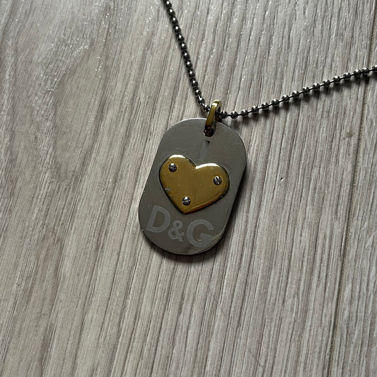 Dolce &amp; Gabbana "I ❤️ D&G" Gold Dog Tag Necklace with a silver stainless steel ball chain, featuring a dog tag engraved with a light "I", a gold metal heart with 3 visible screws, and "D&G" text below, forming the "I ❤️ D&G" design. A playful and collectible vintage piece.