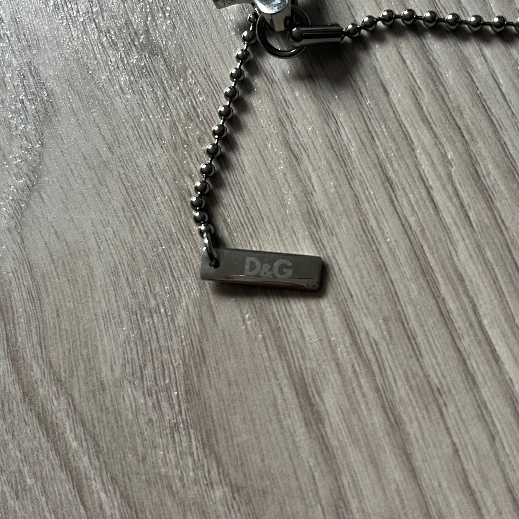 Dolce & Gabbana "I ❤️ D&G" Gold Dog Tag Necklace with a silver stainless steel ball chain, featuring a dog tag engraved with a light "I", a gold metal heart with 3 visible screws, and "D&G" text below, forming the "I ❤️ D&G" design. A playful and collectible vintage piece.