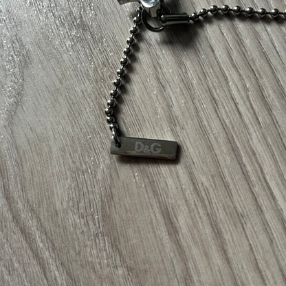 Dolce & Gabbana "I ❤️ D&G" Gold Dog Tag Necklace with a silver stainless steel ball chain, featuring a dog tag engraved with a light "I", a gold metal heart with 3 visible screws, and "D&G" text below, forming the "I ❤️ D&G" design. A playful and collectible vintage piece.