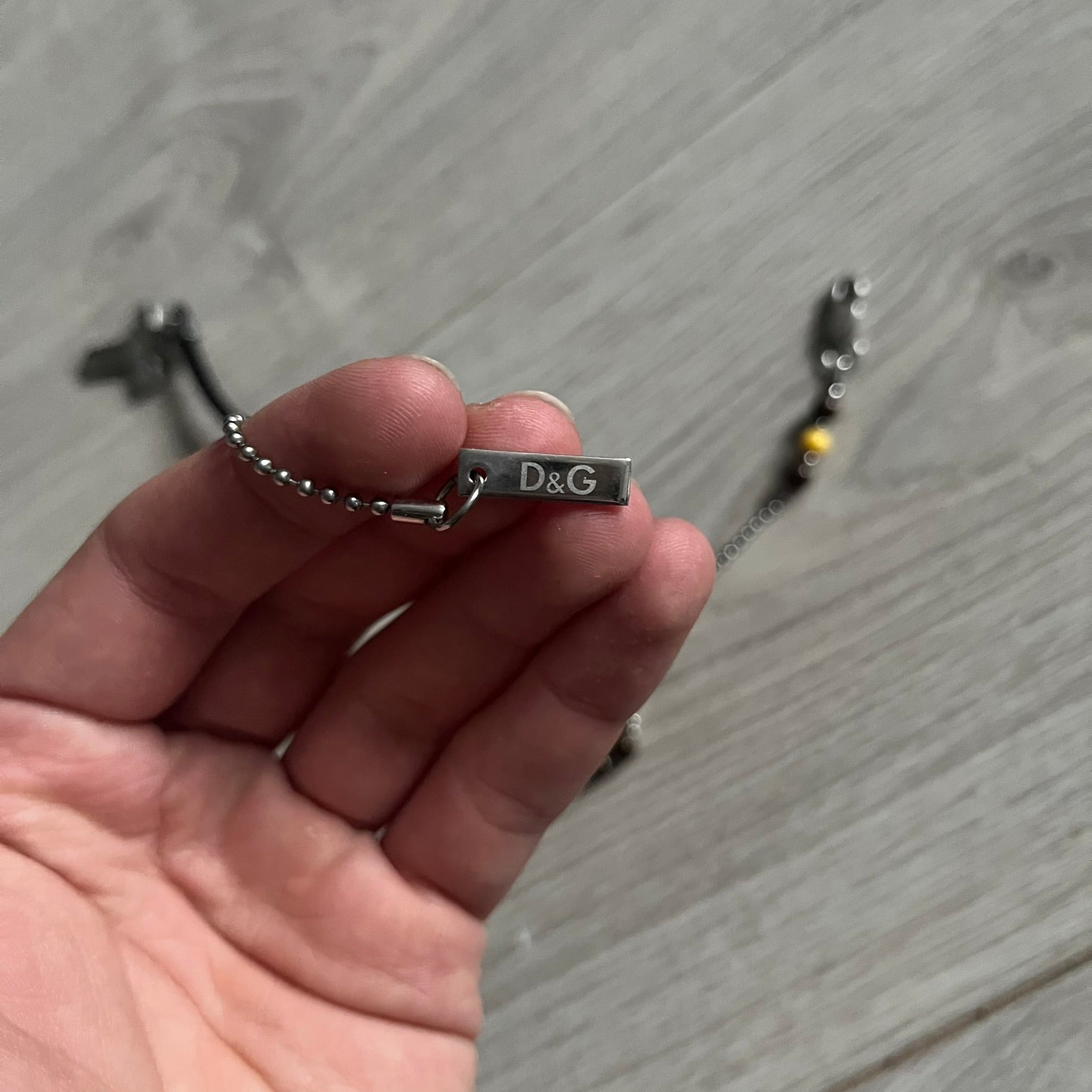 Dolce & Gabbana Pearl Brown Rosary Necklace from the 2000s era. The necklace features a silver-tone metal cross with a D&G logo, connected via a black leather link to a metal chain with alternating brown and yellow pearl-style beads. Rosary-style construction with mixed materials including metal, leather, and resin pearls. Comes complete with the original box.