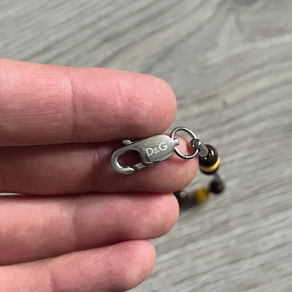 Dolce & Gabbana Pearl Brown Rosary Necklace from the 2000s era. The necklace features a silver-tone metal cross with a D&G logo, connected via a black leather link to a metal chain with alternating brown and yellow pearl-style beads. Rosary-style construction with mixed materials including metal, leather, and resin pearls. Comes complete with the original box.