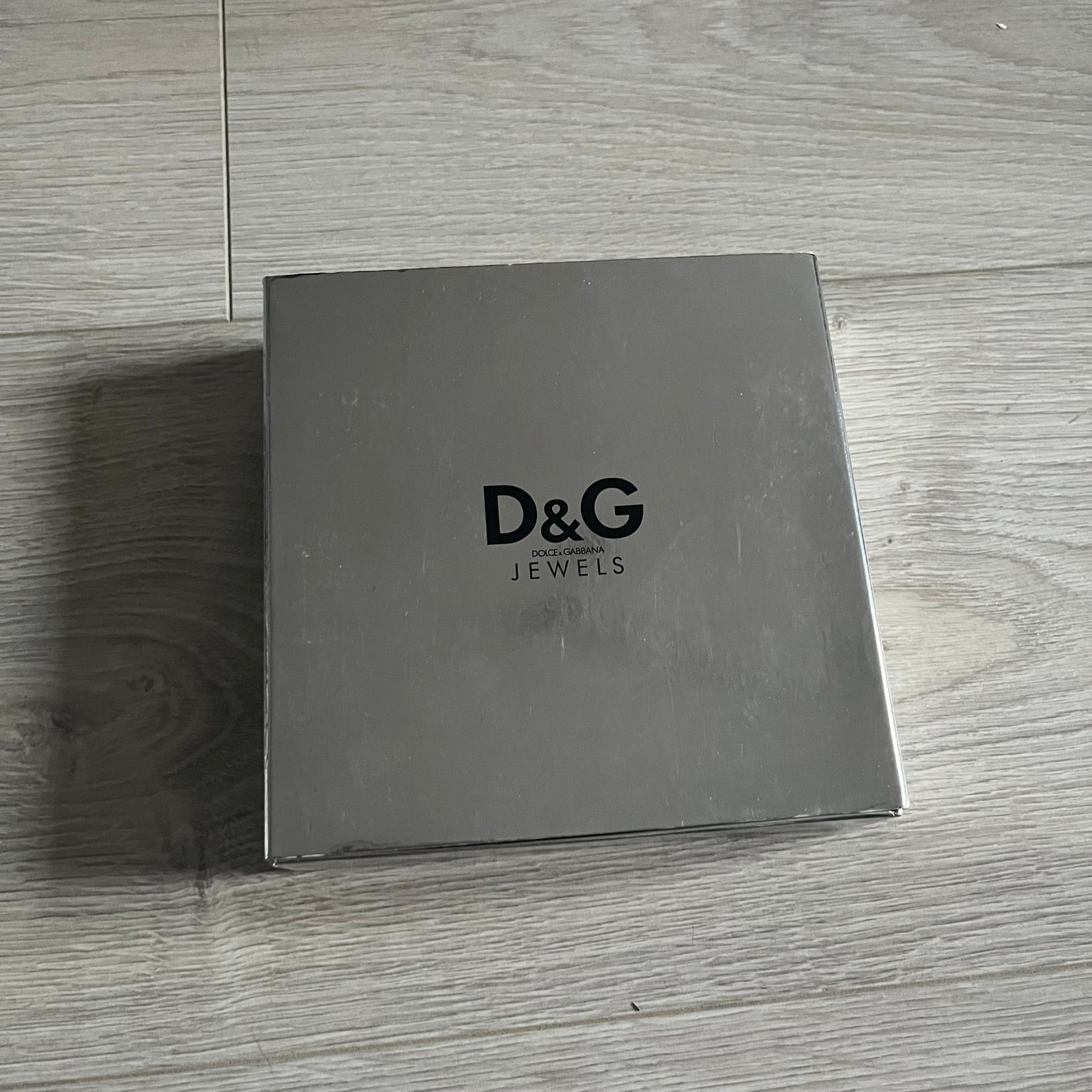 Dolce & Gabbana Pearl Brown Rosary Necklace from the 2000s era. The necklace features a silver-tone metal cross with a D&G logo, connected via a black leather link to a metal chain with alternating brown and yellow pearl-style beads. Rosary-style construction with mixed materials including metal, leather, and resin pearls. Comes complete with the original box.