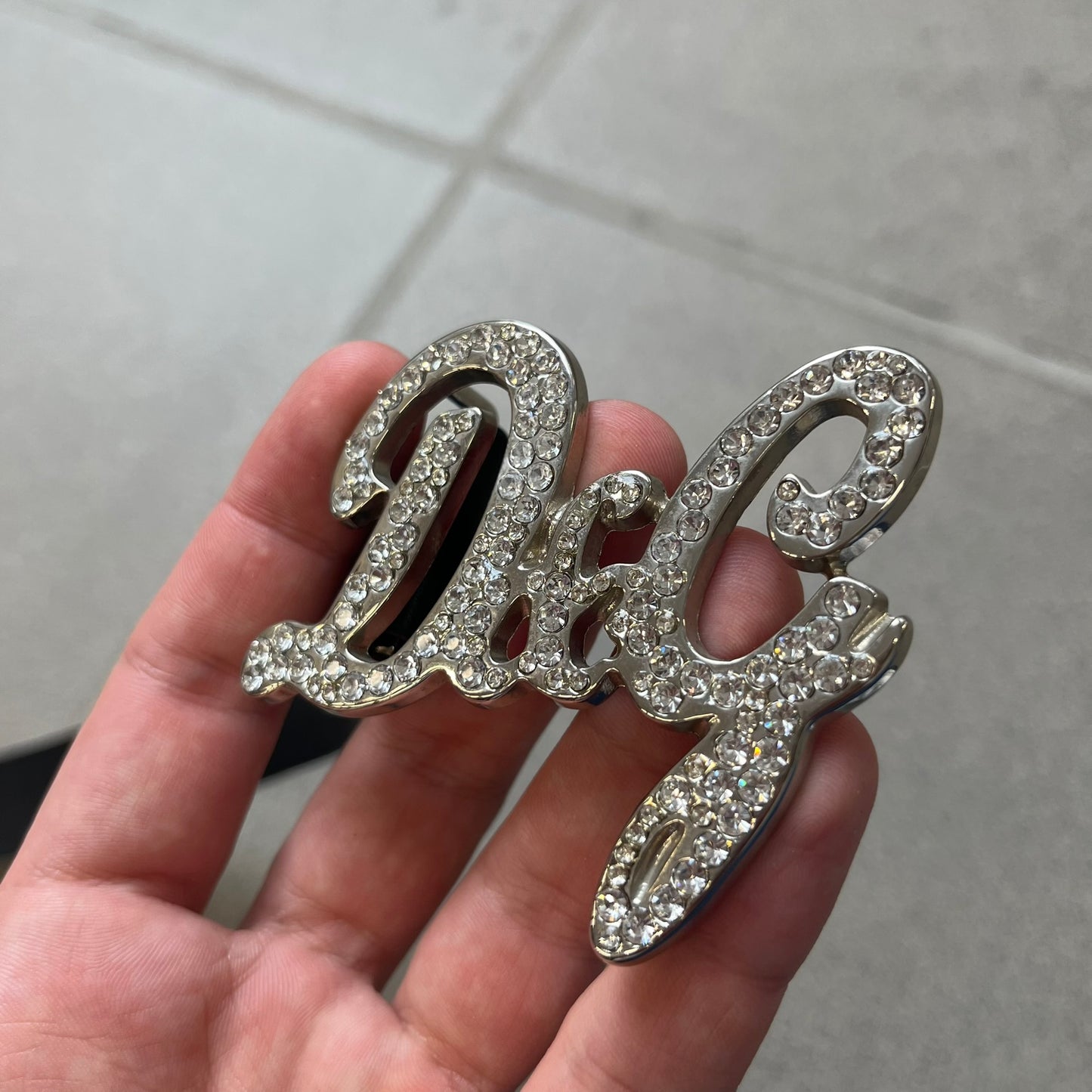 Dolce &amp; Gabbana 2000s Black Crystal Buckle Belt features a black leather strap with a stainless steel D&amp;G logo buckle. The buckle has a decorative italic-style font and is fully covered with crystal/rhinestone detailing on the front. Made in Italy.