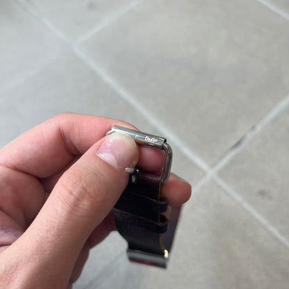 Dolce & Gabbana 2000's Brown Leather Bracelet features brown leather straps with an adjustable fit and a stainless steel central plaque. The plaque has a raised wavy texture on the front and a D&G logo underneath, while the leather straps have small D&G and “Genuine Leather” tags.
