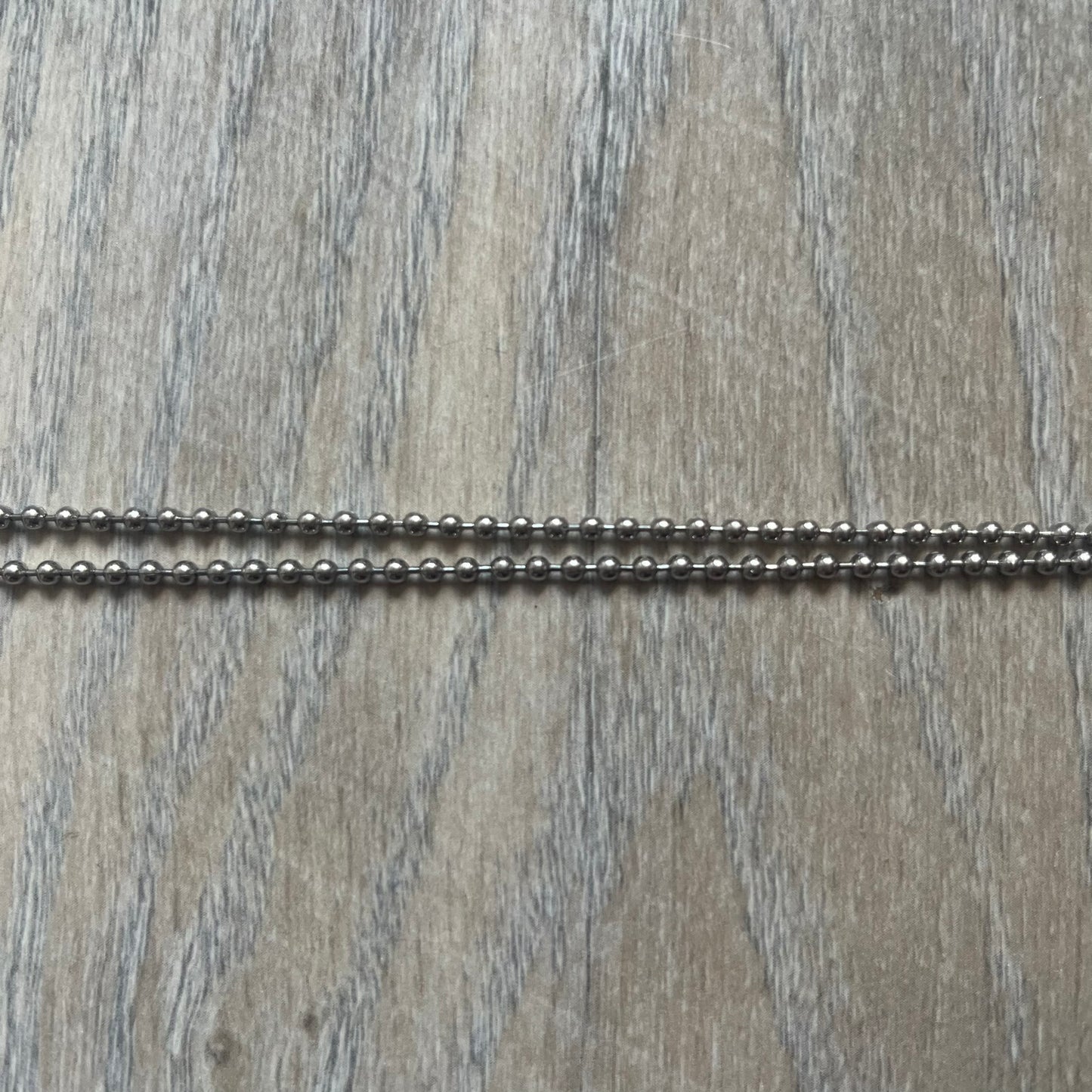 Dolce &amp; Gabbana Cowboy Dog Tag Necklace, model DJ0633. Features a silver-tone metal ball chain and a dog tag with black cowboy-style D&amp;G logo and small “Dolce &amp; Gabbana” text underneath. The front of the tag is patterned with subtle white dots for added detail.