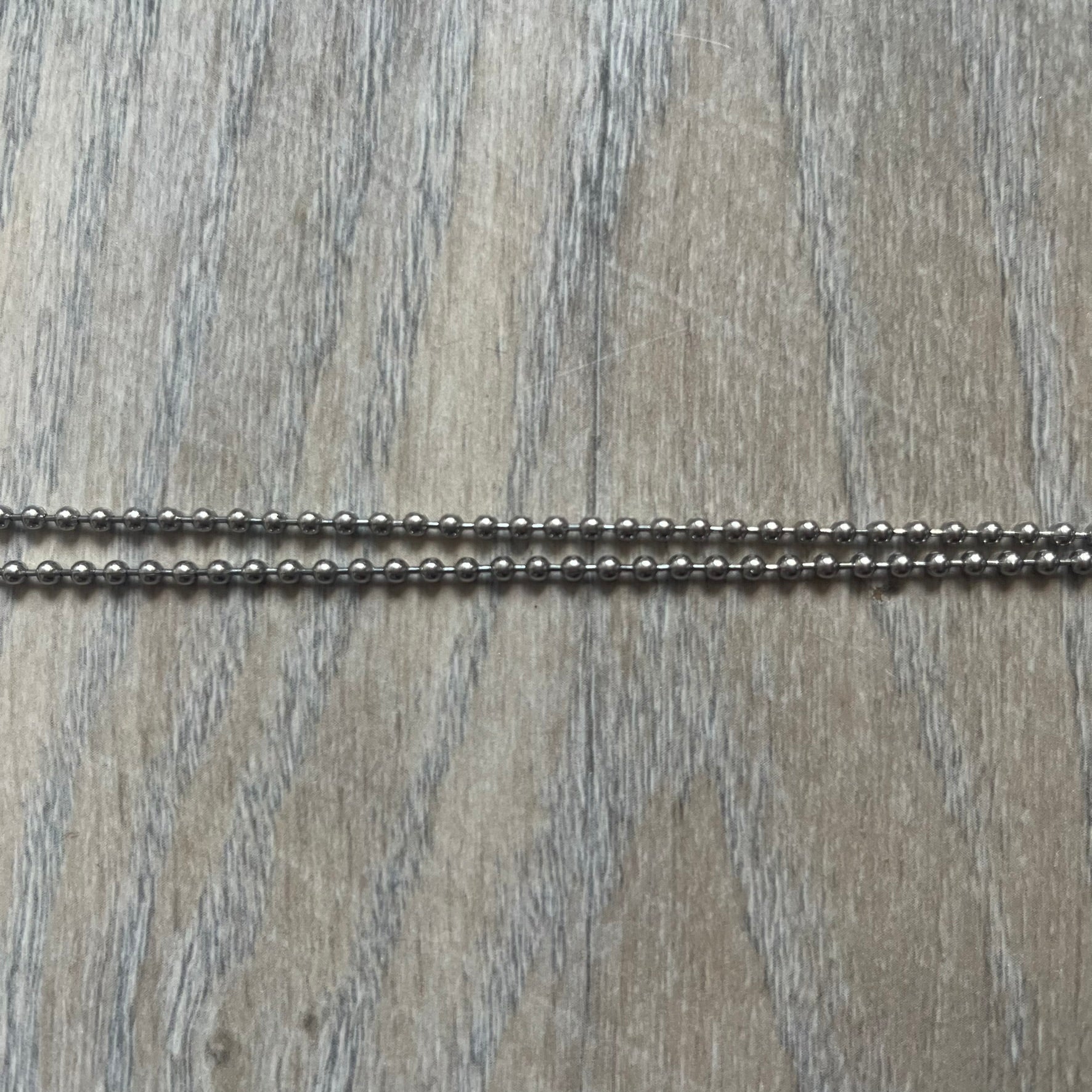 Dolce &amp; Gabbana Cowboy Dog Tag Necklace, model DJ0633. Features a silver-tone metal ball chain and a dog tag with black cowboy-style D&amp;G logo and small “Dolce &amp; Gabbana” text underneath. The front of the tag is patterned with subtle white dots for added detail.