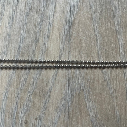 Dolce &amp; Gabbana Cowboy Dog Tag Necklace, model DJ0633. Features a silver-tone metal ball chain and a dog tag with black cowboy-style D&amp;G logo and small “Dolce &amp; Gabbana” text underneath. The front of the tag is patterned with subtle white dots for added detail.